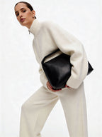 Жінка в молочному вʼязаному костюмі Merin із 100% мериносу із сумкою на білому фоні, вид спереду