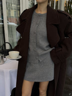 Жінка в коричневому максі пальто Muse тримає чашку кави, вид зблизька