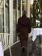 Жінка в коричневому максі пальто Muse в русі, вид позаду